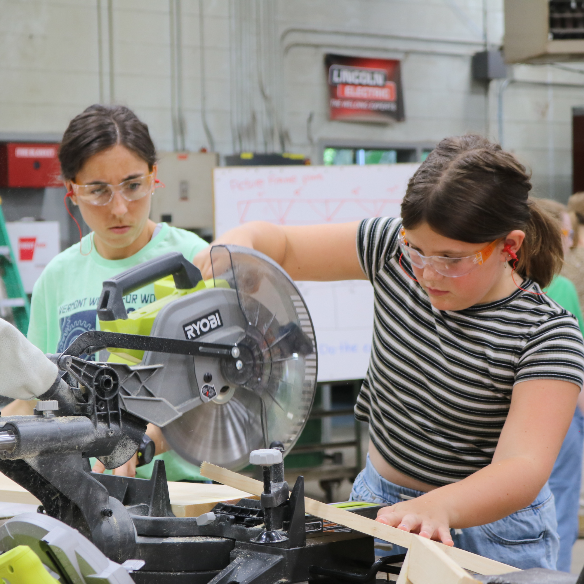 Rosie's Girls camper uses a miter saw to cut wood at Rosie's Girls BUILD summer camp