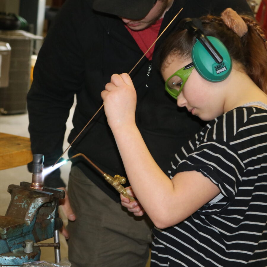 Middle School student learns how to solder pipes at Career Challenge Day