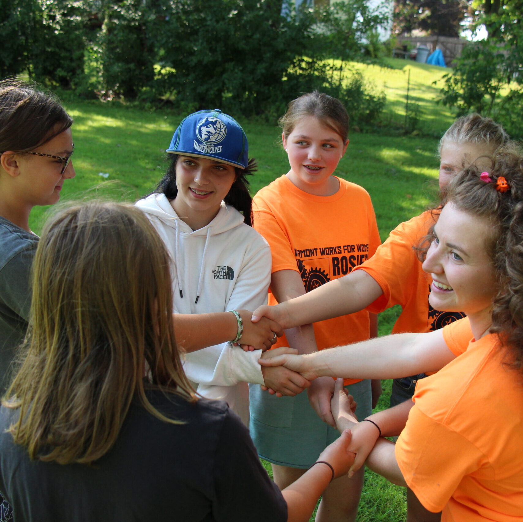Rosie's Girls campers play a game outside holding hands at summer camp.