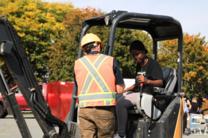 Student tries operating a back hoe at Women Can Do