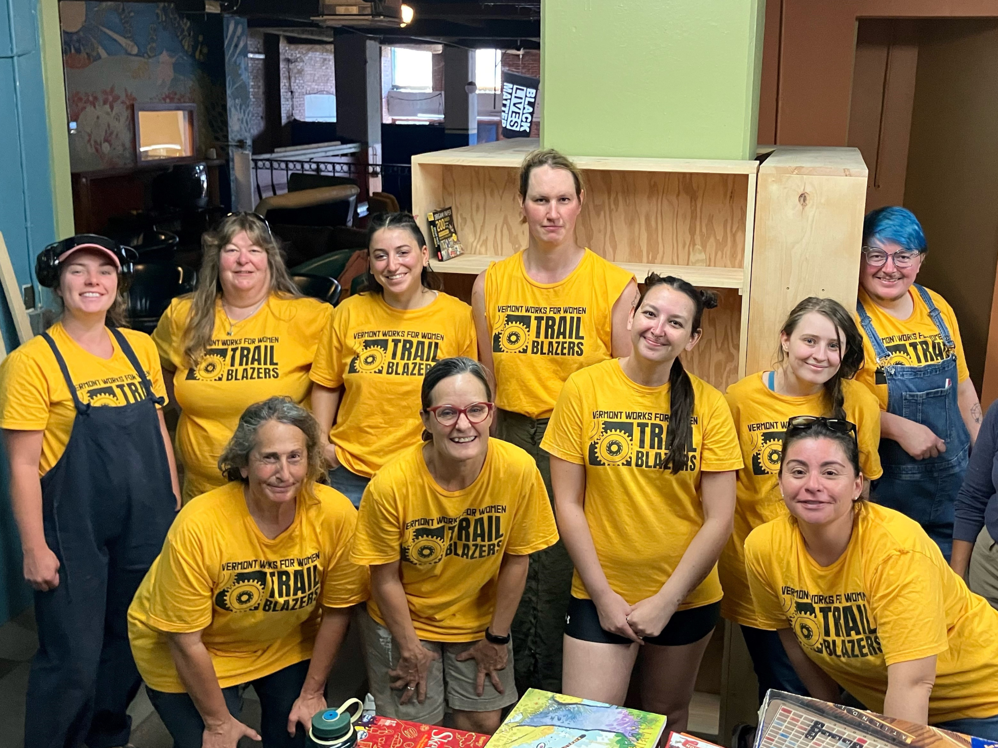 2024 Brattleboro Trailblazers graduates pose in front of shelves they built for the Boys and Girls Club.