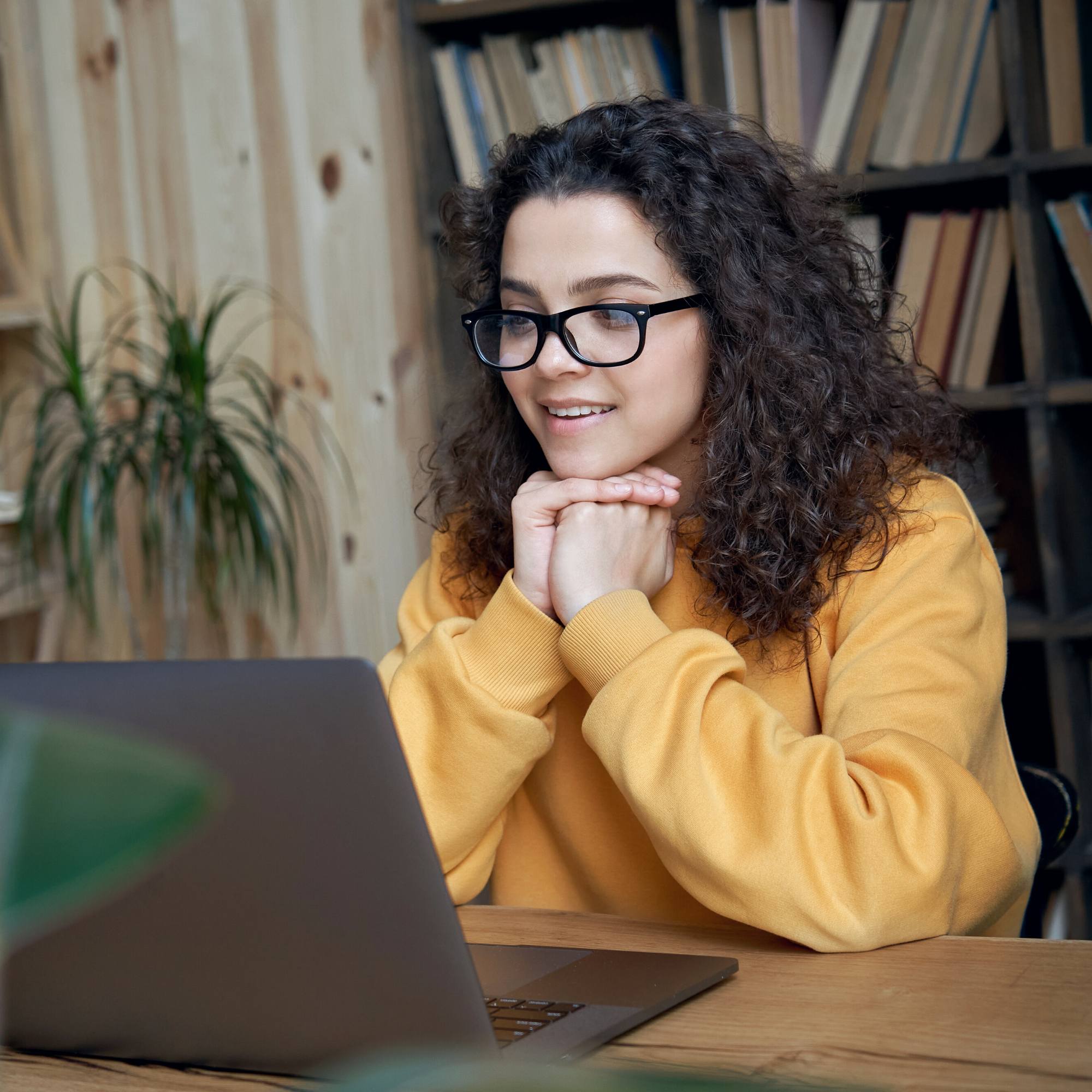 Young woman looks at a computer screen representing how mentees can connect with Vermont Works for Women's career mentors.