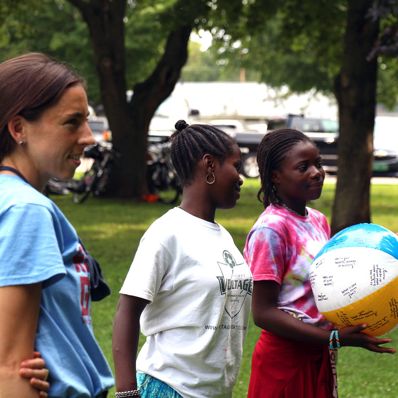 VWW staff member stands with two Rosie’s Girls campers. One camper is holding a beach ball for a name game. Donating to Vermont Works for Women is the best way to support programs like these.