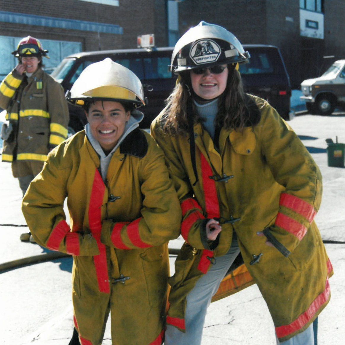 Two girls in firefighting gear pose for a photo. Vermont Works for Women's history dates back to 1987.