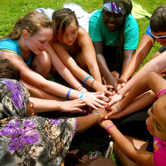Campers put their hands together. Vermont Works for Women's history dates back to 1987.