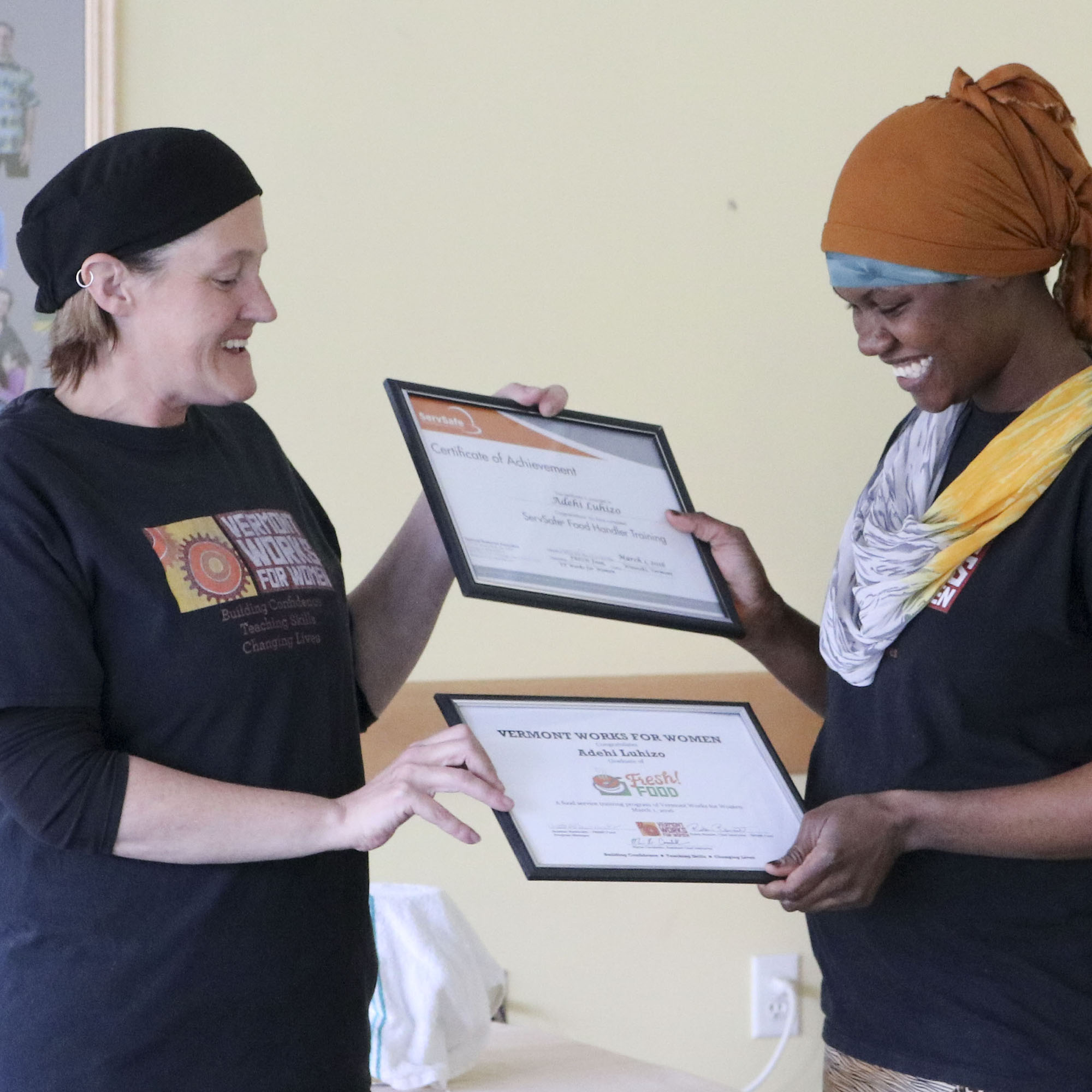Vermont Works for Women's staff member hands a graduation certificate to a participant. Fresh Foods is a past program of VWW.