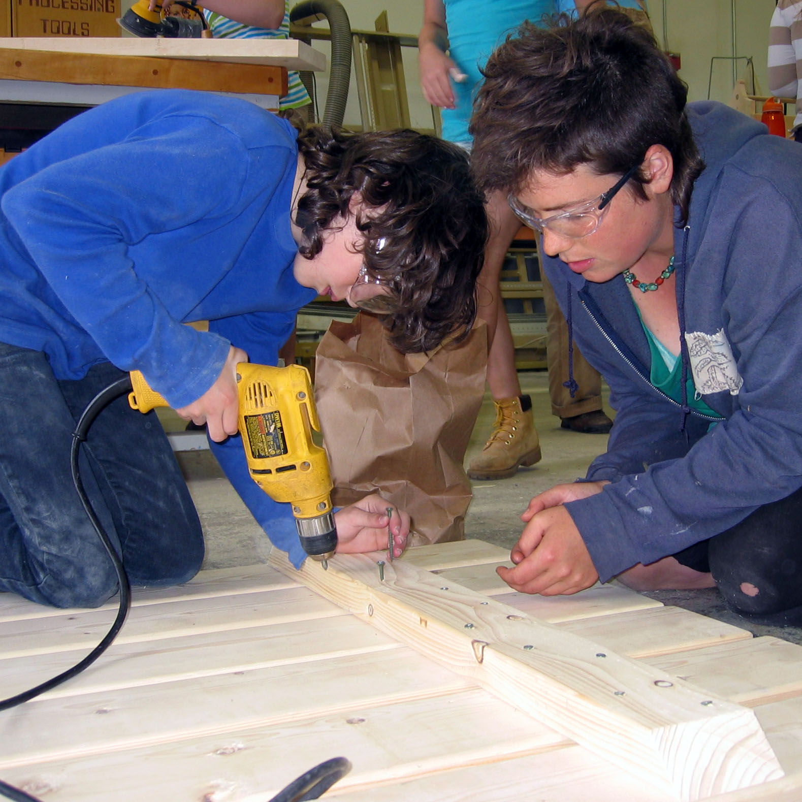 Two campers use a screw gun to work on a wood project. Rosie's Girls camp has been around since 2000.