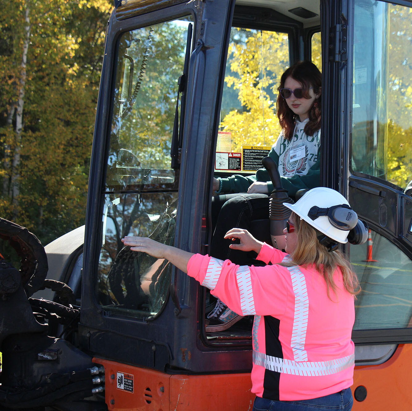 A student sits in the cab of a backhoe while a female operator instructs her how to excavate at Women Can Do. Introducing girls to a variety of career opportunities is a part of Vermont Works for Women's overall mission.