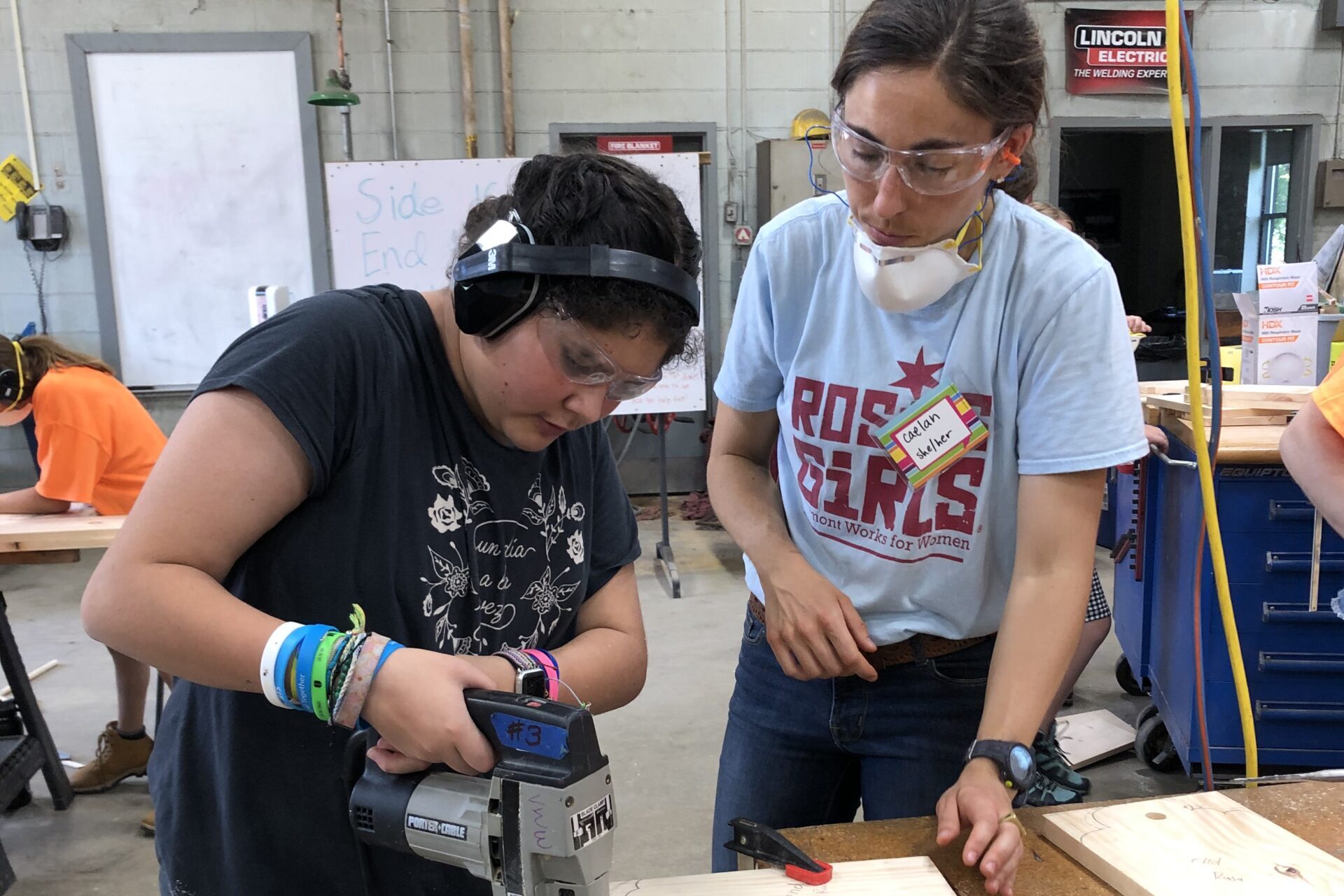 A Rosie's Girls instructor oversees a camper using a jigsaw at one of Vermont Works for Women's summer programs.