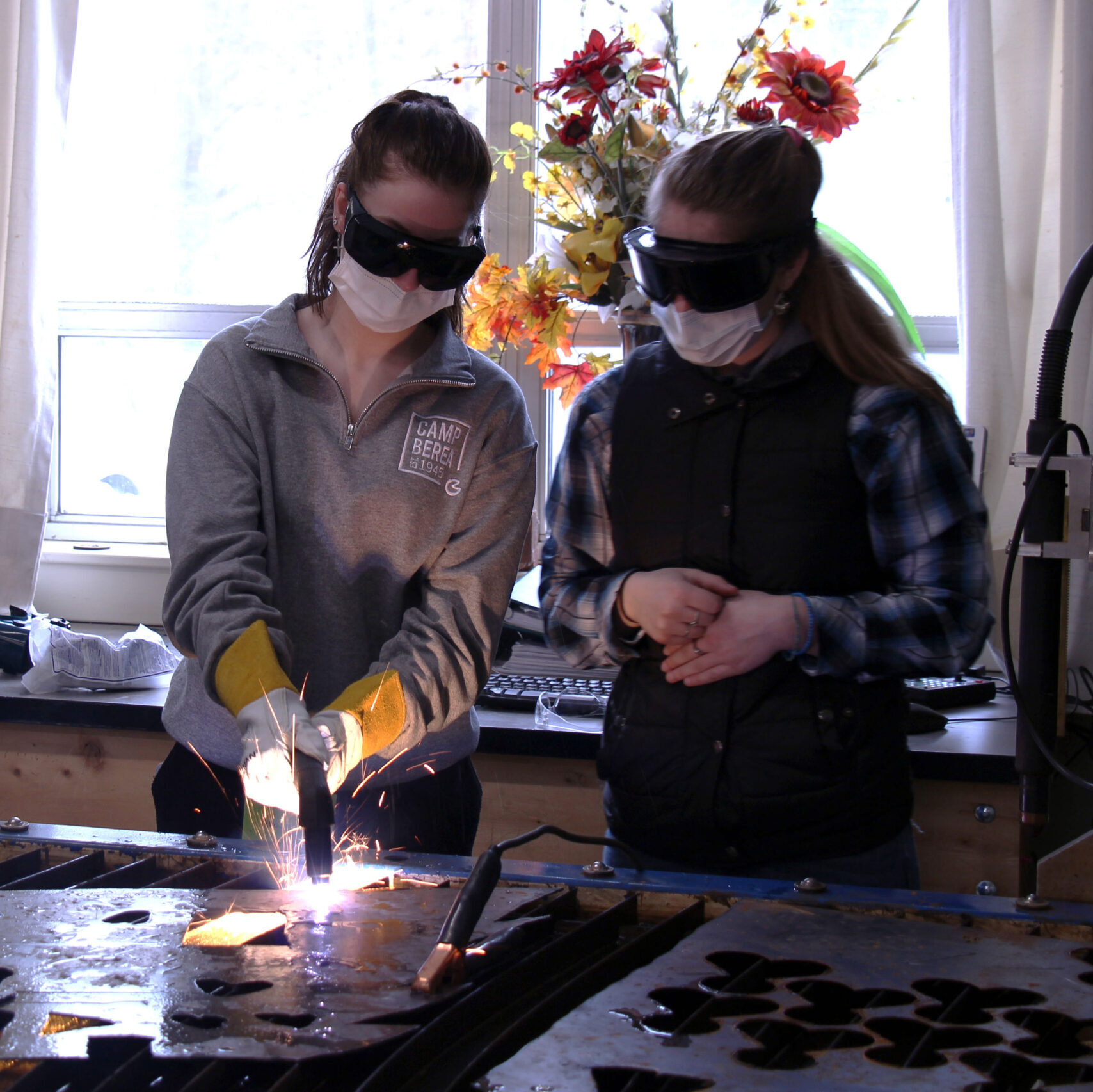 Two high school girls use a plasma cutter at Career Challenge Day, one of the events that Vermont Works for Women offers tech centers as an engagement opportunity for middle school youth.
