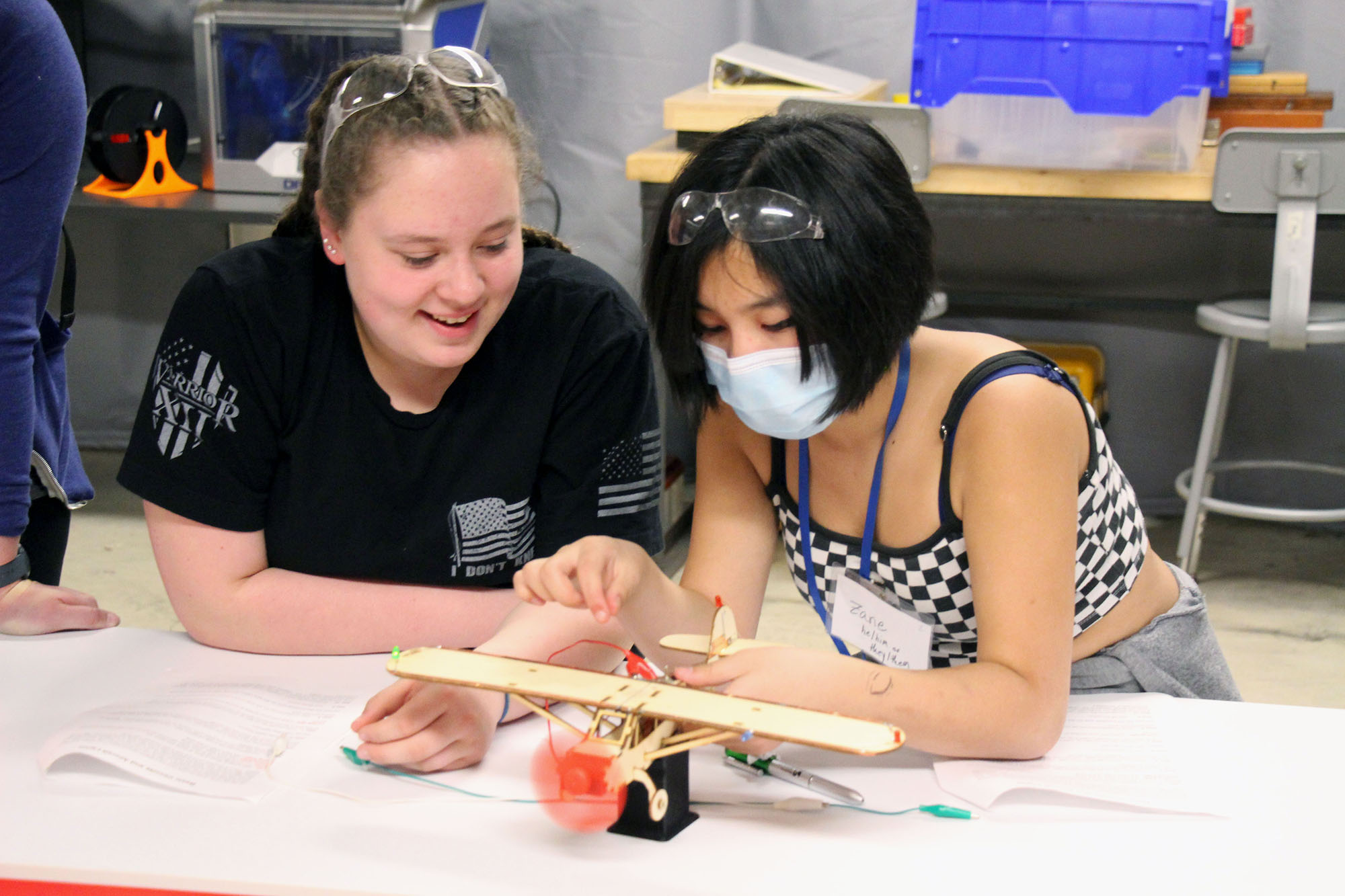 4. Students use wires and circuits to make a propeller spin on a wooden model plane.