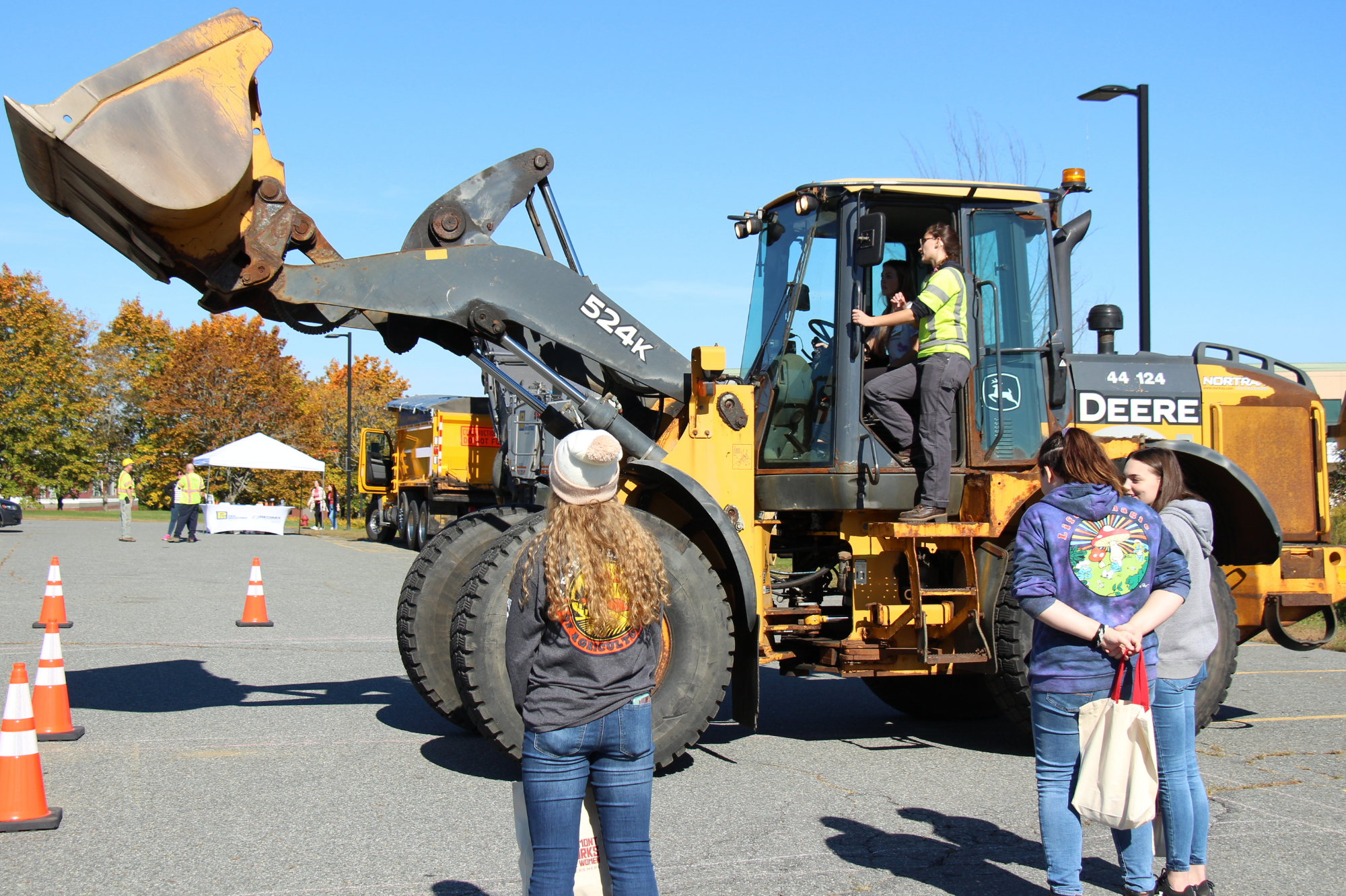High school students look on as another student learns to operate a backhoe.