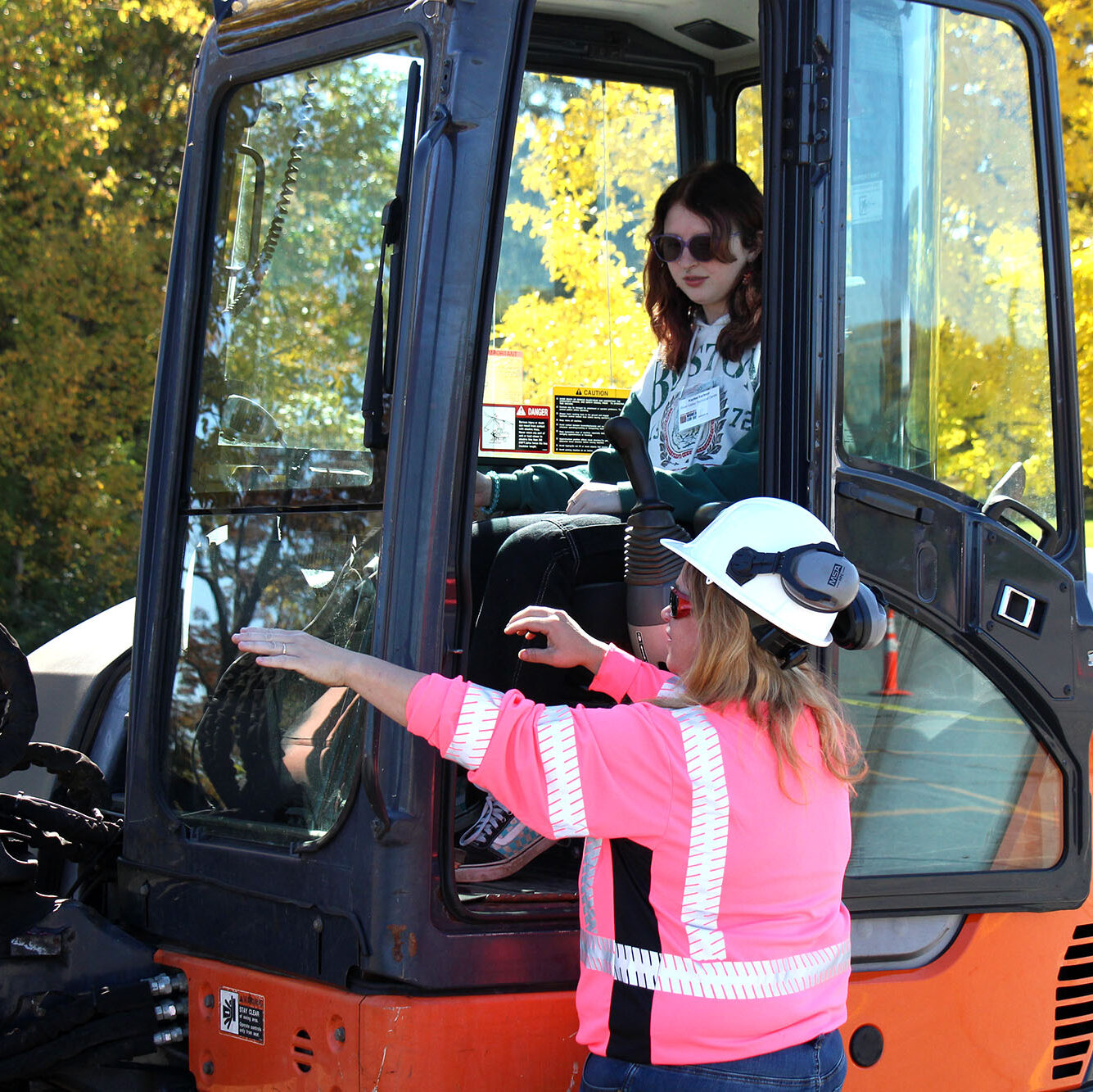 A female student sits in the cab of a backhoe at Women Can Do’s Outdoor Action Expo