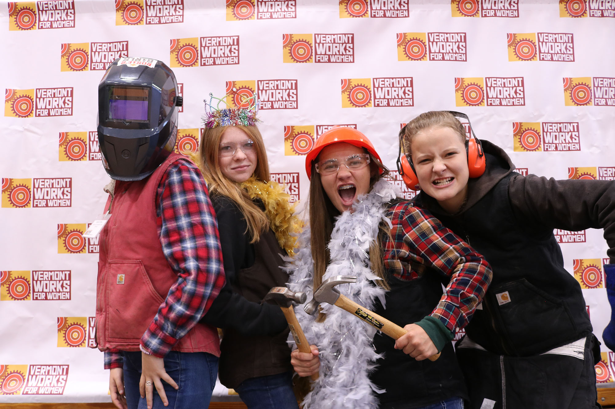 Students pose in photo booth wearing costumes and construction gear at Women Can Do.