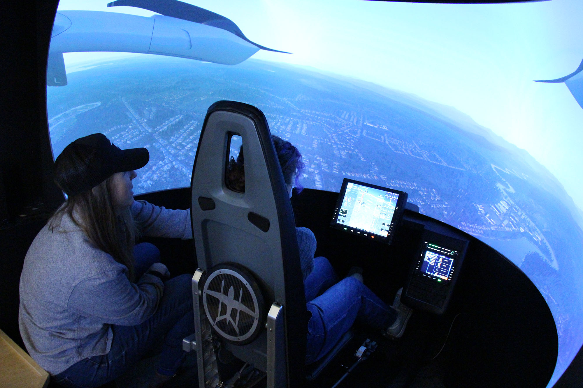 Student sits in BETA Technology’s electric plane flight simulator at Women Can Do.
