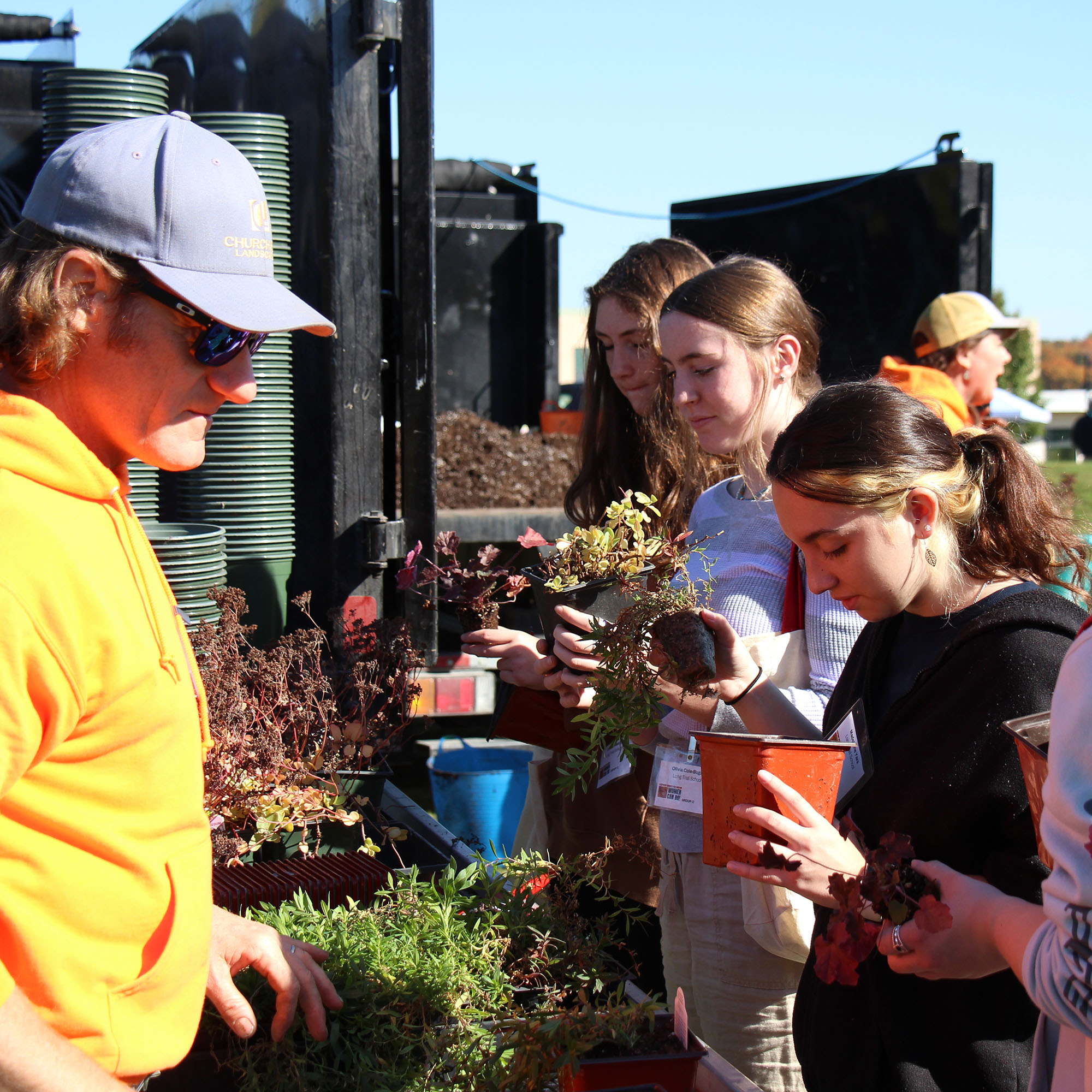 A group of high school girls put plants into pots. Schools, businesses, and volunteers come together to provide an impactful experience for more than 250 students at the conference.