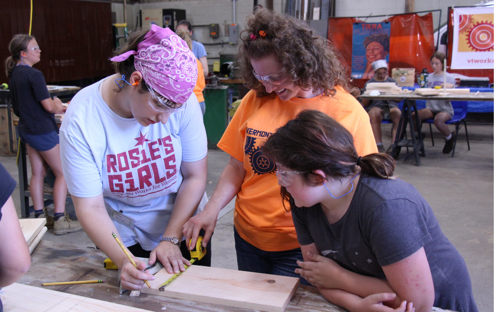 Instructors demostrate how to measure wood at Rosie's Girls Summer Camp.