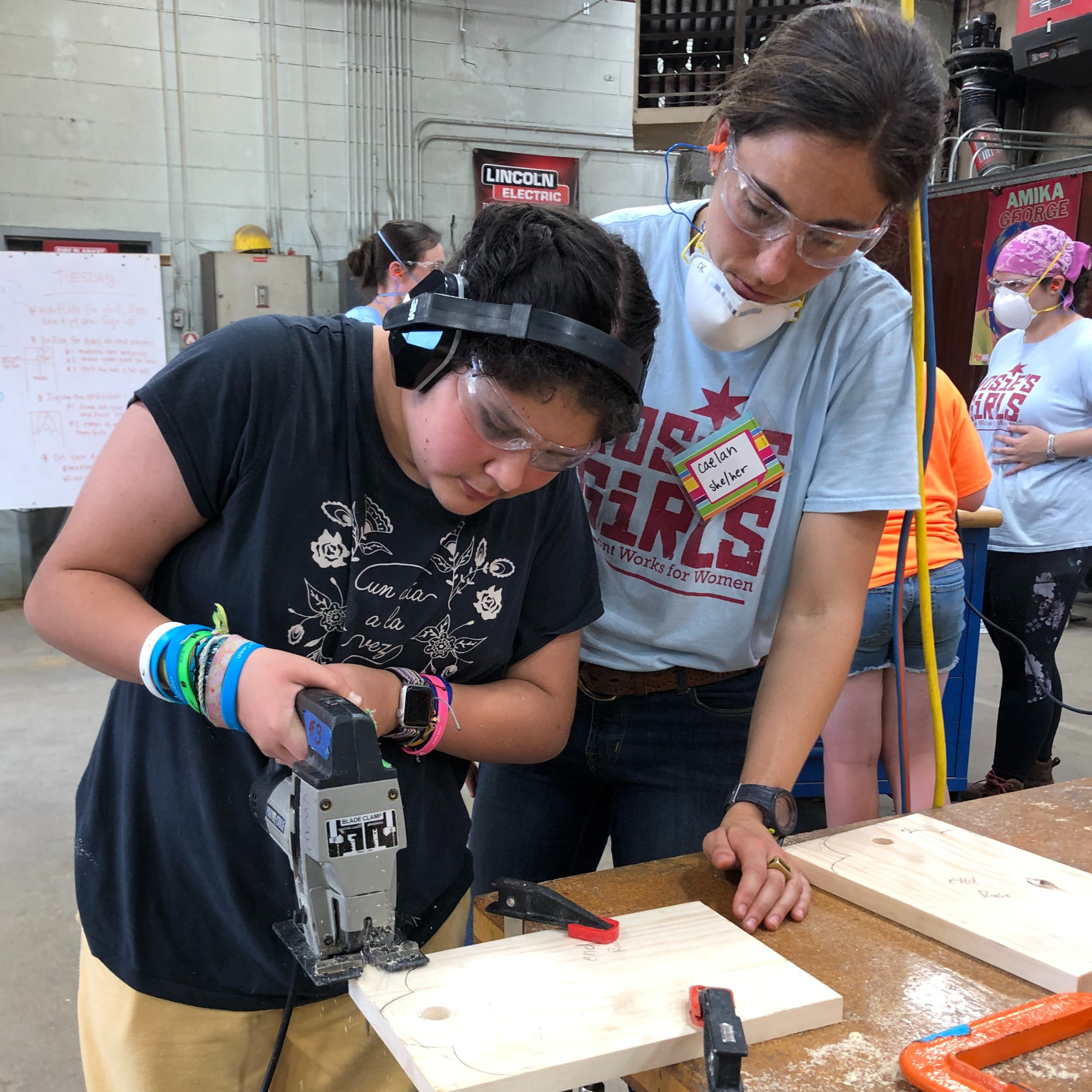 Camper uses a power tool to cute wood at Rosie's Girls Summer Camp