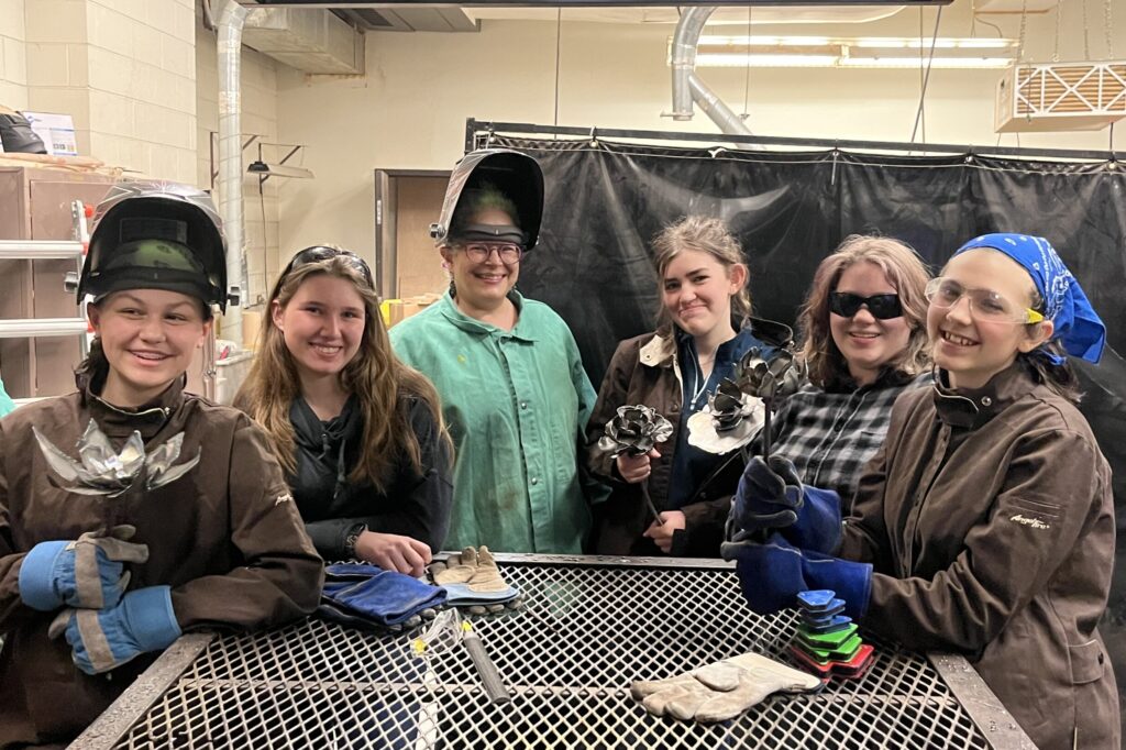 A group of middle school students pose for a photo, holding their custom weld projects, during Rosie's Girls Afterschool in Montpelier, VT.