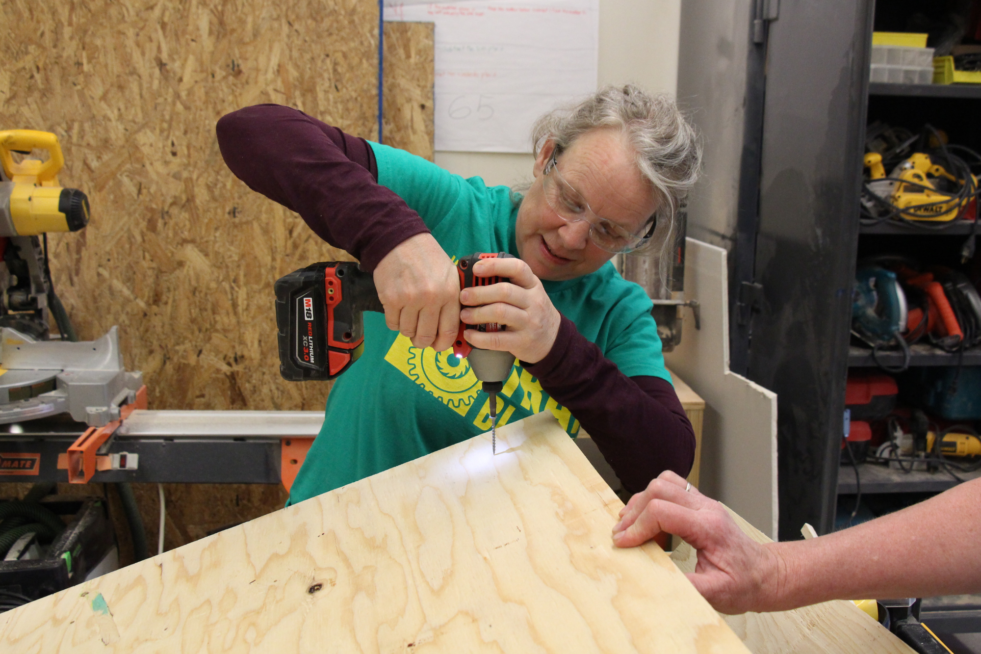 Trailblazers participant uses a cordless drill to screw plywood.