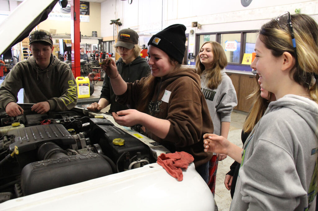 A middle school student checks the oil in a test vehicle at a local career and technical center as part of Career Challenge Day - an event hosted by Vermont Works for Women to introduce youth to programs.