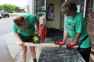 Trailblazers use a saw to cut wood outside of the VWW offices.