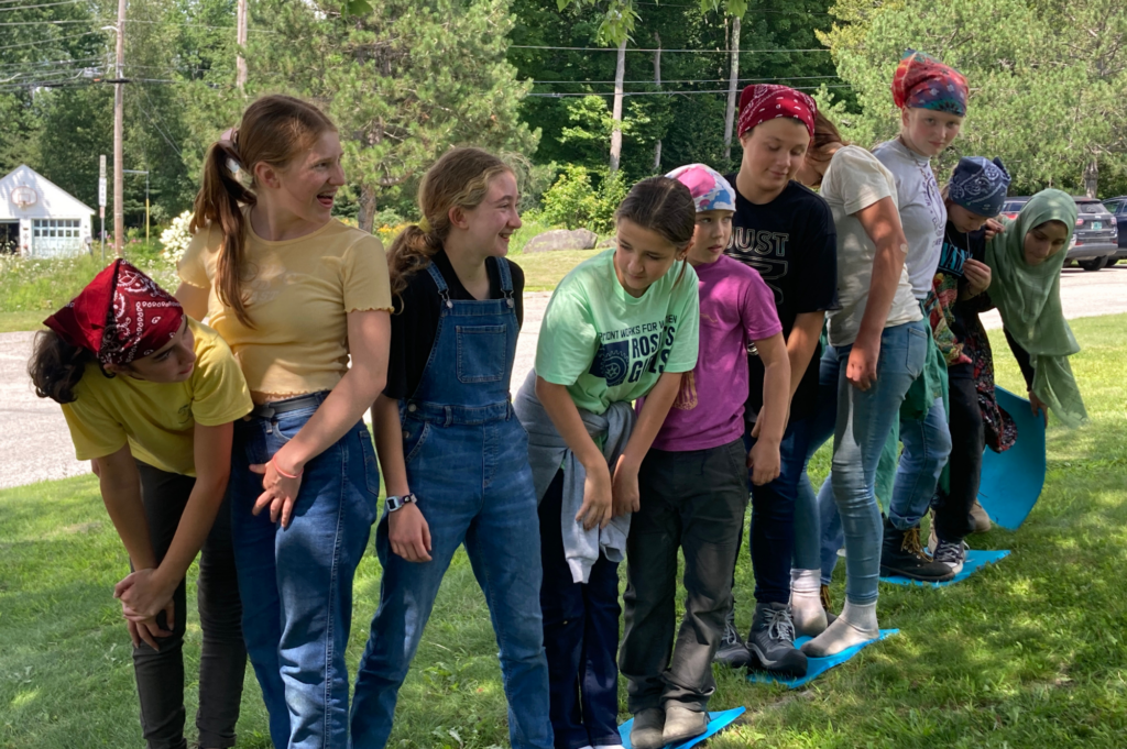 Rosie's Girls campers play team building games on the grass.