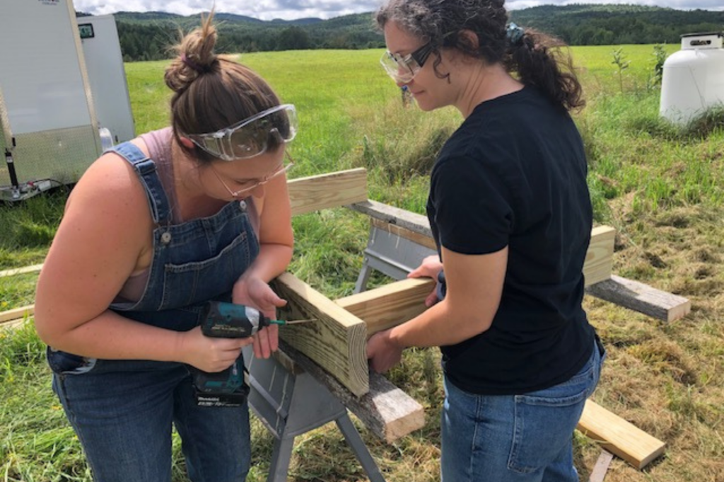 One Trailblazer drills a screw while the other holds a board steady