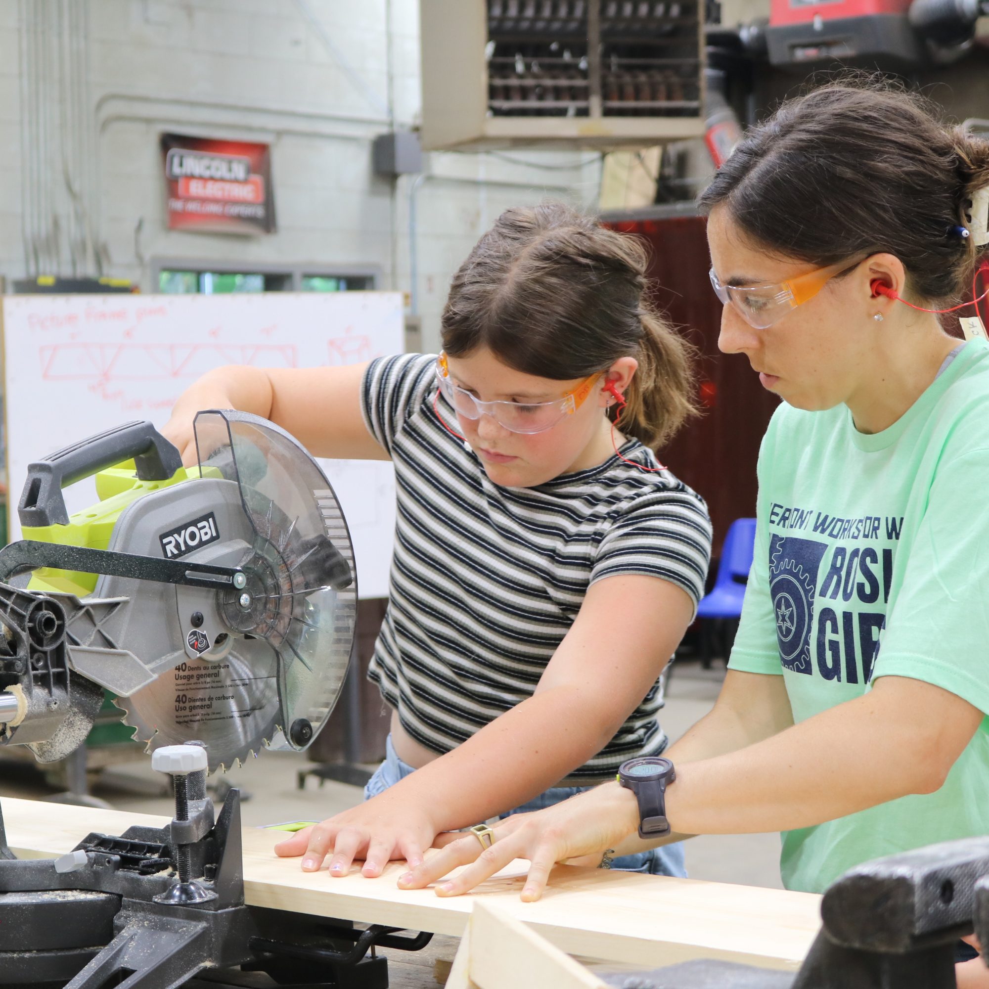 VWW staff member helps a Rosie's Girls camper to cut lumber with a chop saw.