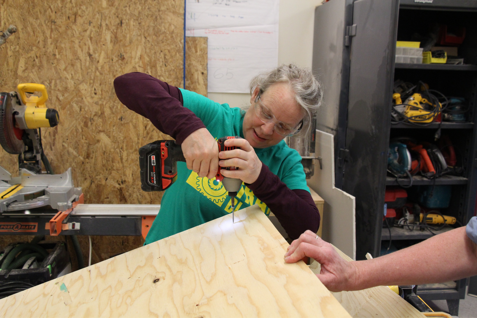 Trailblazers uses drill to screw a piece of plywood.