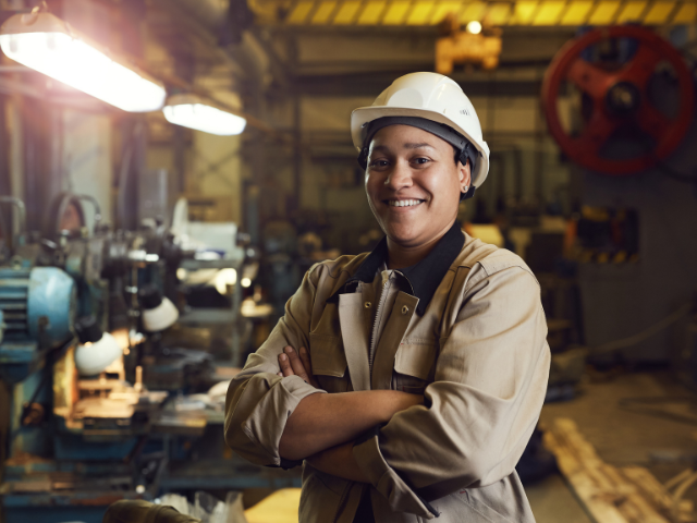 Woman stands proudly in mechanical shop