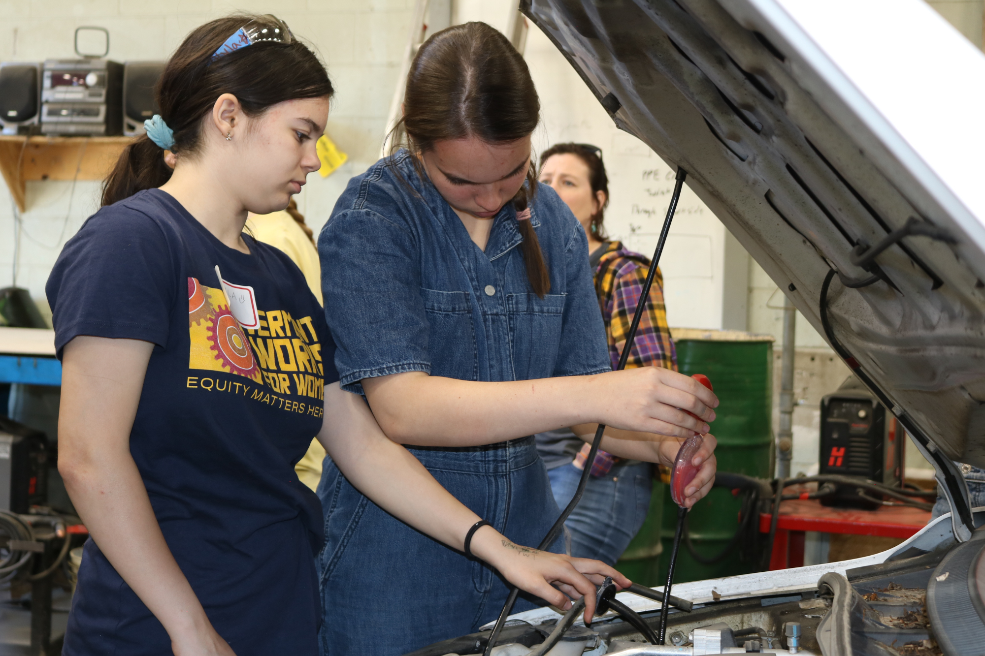 High school girls check fluid levels in car during the automotive day at LIFT.