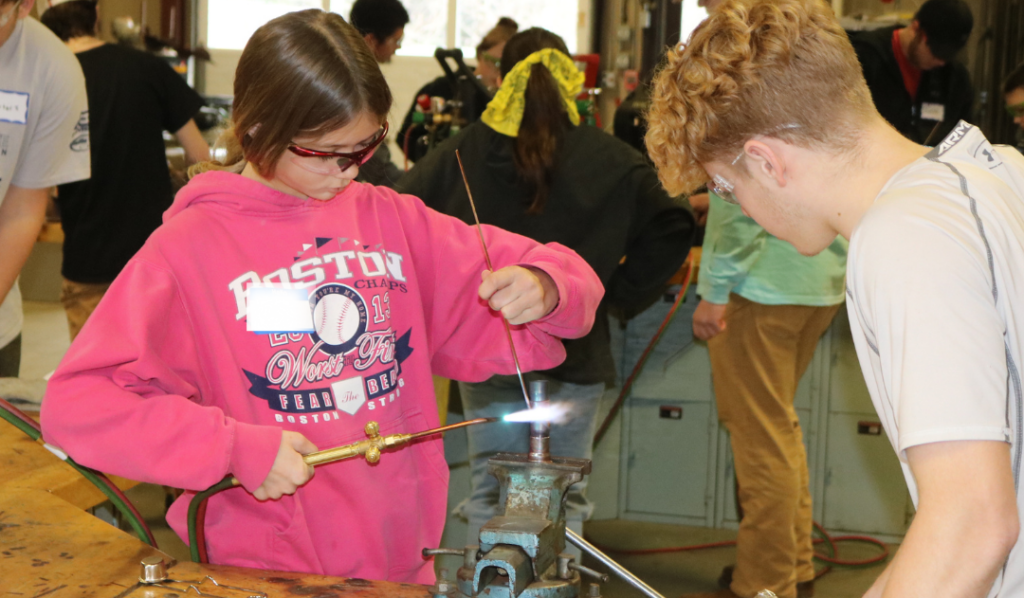 Middle school girl brazes copper pipes at Career Challenge day at GMTCC.