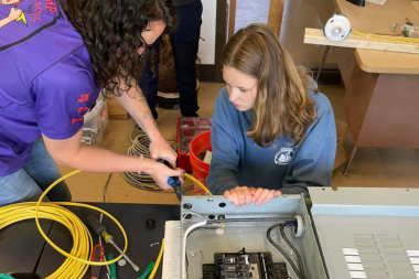 Alli at AMP Electric shows a Trailblazer how to wire an electrical panel.