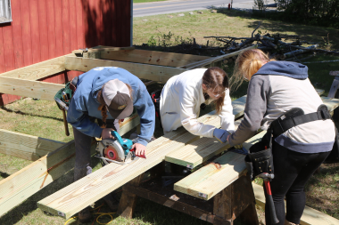 Trailblazers use a circular saw to cut lumber while building a deck.