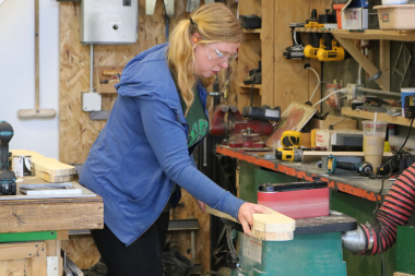 A Trailblazer uses a sander to smooth a board.