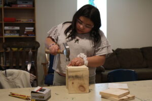 Student uses hammer to make birdhouse