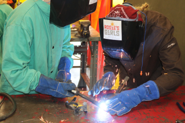 Rosie's Girls camper uses a plasma cutter to cut metal flowers.