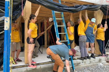 Trailblazers hold up tarp at Timberframe build site