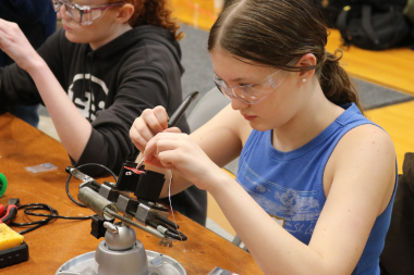 Student solders metal at Women Can Do Indoor Action Expo