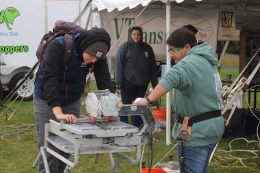 A tech center student shows a high school student how to use a table saw at Women Can Do 2024