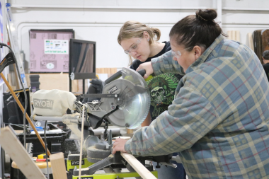 A Trailblazers participant uses a miter saw to cut wood for strapping.