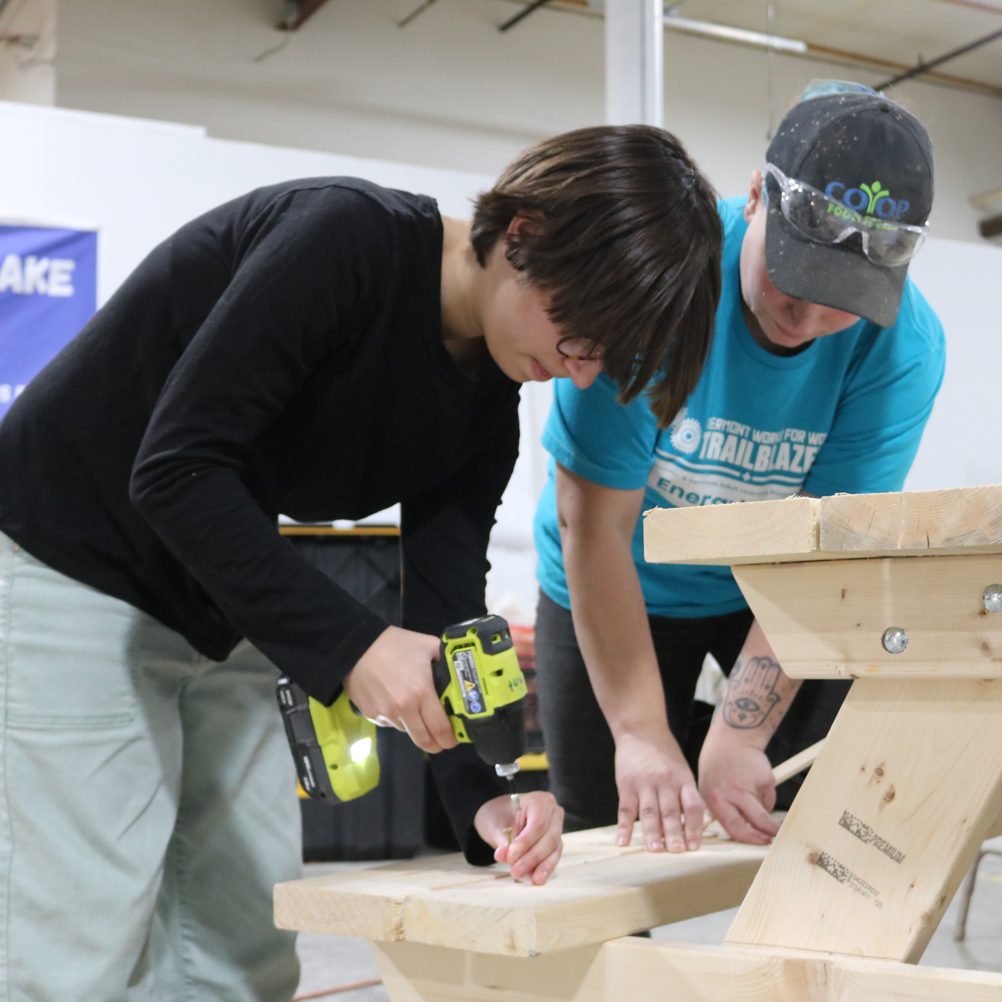 Trailblazers use a drill to build a picnic table for a local non-profit as their service project