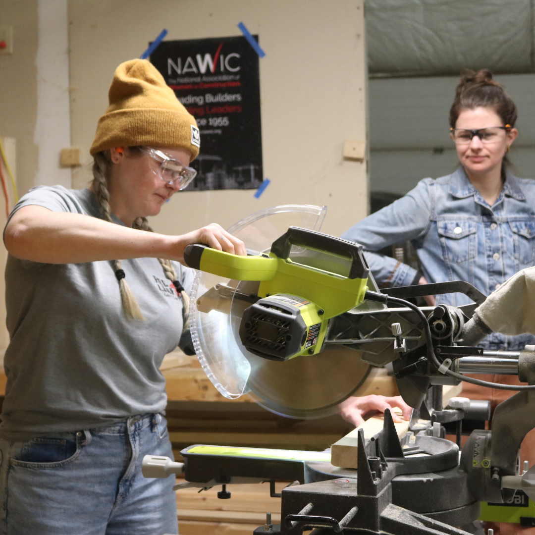 Woman uses a miter saw to cut wood during VWW's Trades training program