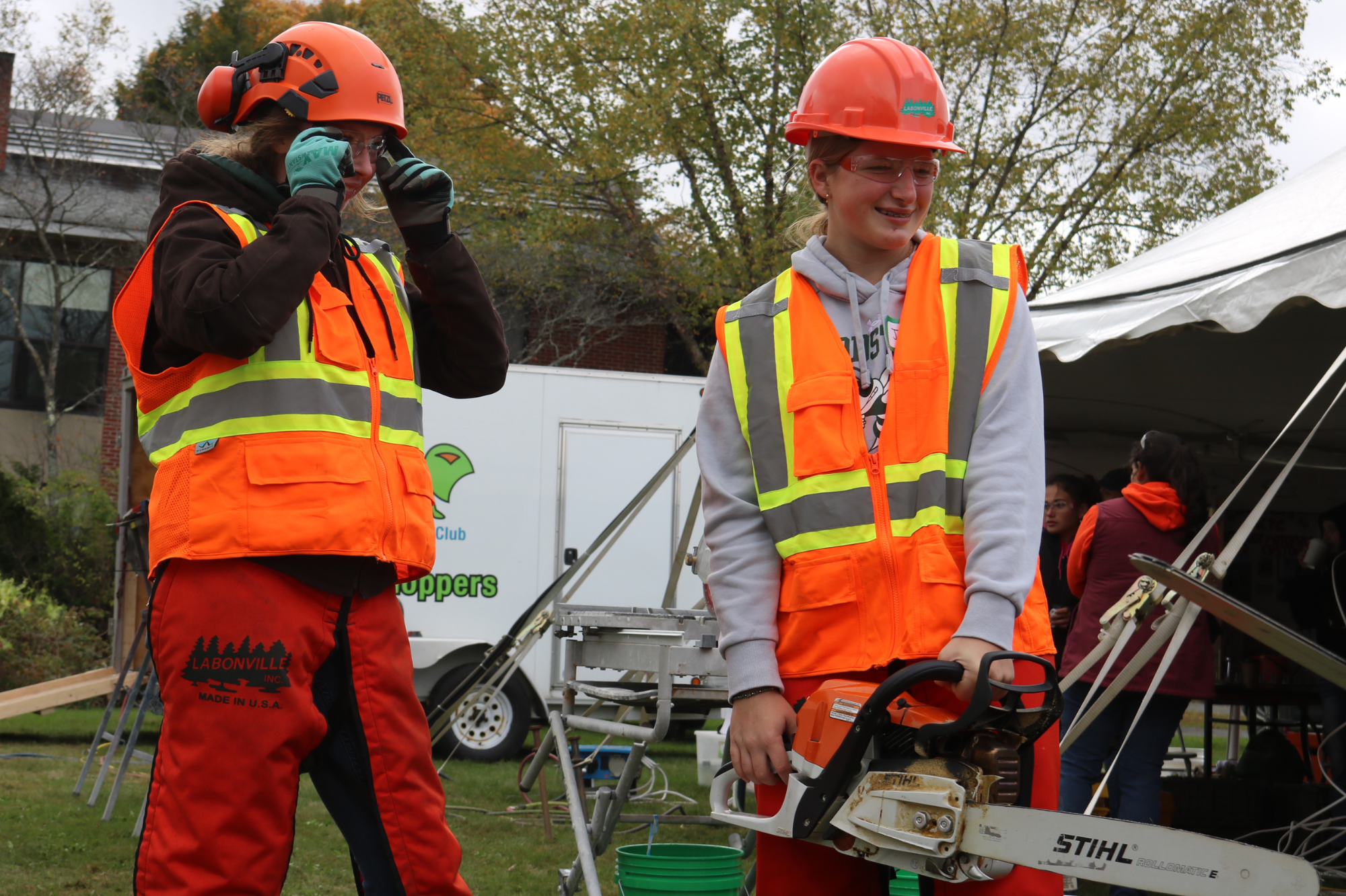 Two students try using a chainsaw at Women Can Do in Randolph.