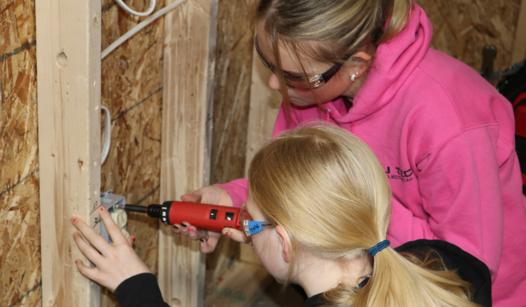 Tech Center student Leah shows a middle school girl how to wire an outlet at Career Challenge Day