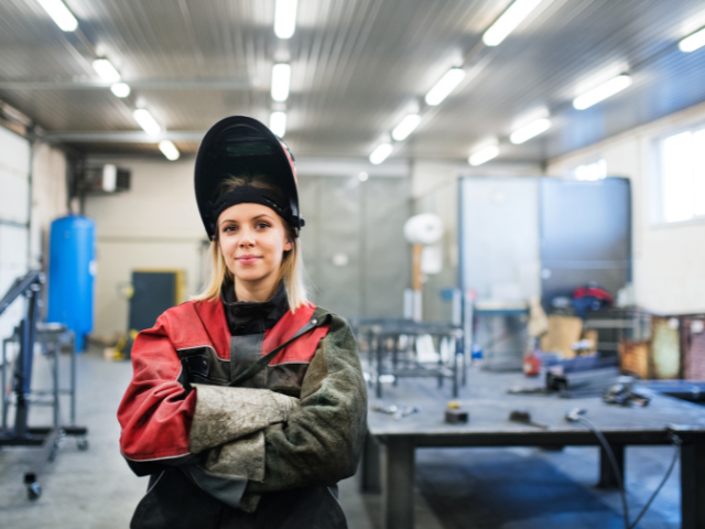 Woman stands in welding gear