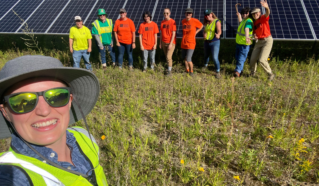 Amber poses with Trailblazers participants in front of solar panel.