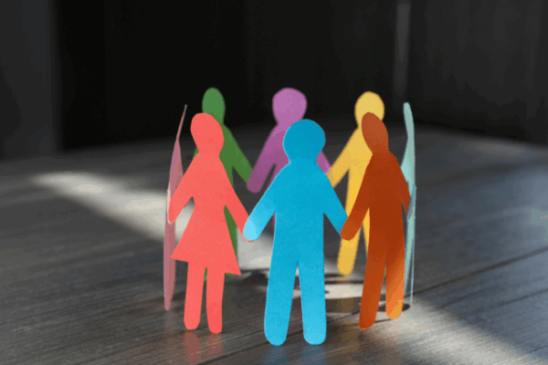 Paper human figures making circle on wooden table
