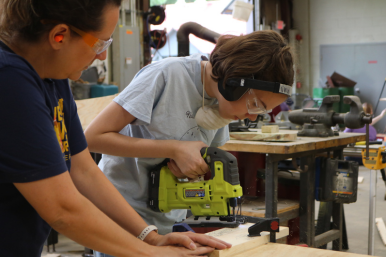 Camper uses a jigsaw to cut wood at Rosie's Girls camp